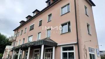 Das Gebäude ist ein Hotel mit Apartments und Geschäften im Erdgeschoss, mit einer rosa Fassade.