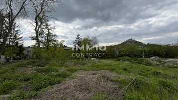 Weitläufiges Grundstück mit viel Grün und Blick auf die umliegende Hügellandschaft unter bewölktem Himmel.
