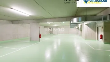 Geräumige und helle Tiefgarage mit glänzendem grünem Boden, Betonwänden und klar markierten Parkplätzen.