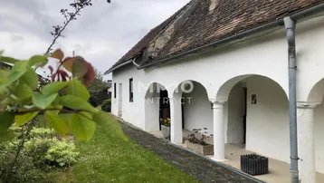 Traditionelles Landhaus mit weißer Fassade, Arkaden und einem gepflegten Gartenbereich.