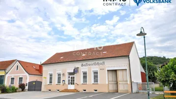 Traditionelles Gasthaus mit Ziegeldach und hell gestrichener Fassade unter bewölktem Himmel.