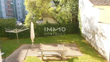 Kleiner Gartenbereich mit gepflasterter Terrasse, Sitzbank und Wäscheständer, umgeben von Grünflächen.