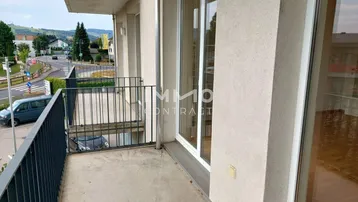 Geräumiger Balkon mit Metallgeländer und Ausblick auf die Umgebung und ferne Hügel.