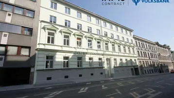 Historisches Gebäude mit klassischer Fassade und vielen Fenstern an einer Stadtstraße.