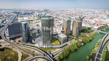 Luftaufnahme einer modernen Stadtlandschaft mit Hochhäusern, Fluss und Autobahnen unter blauem Himmel.