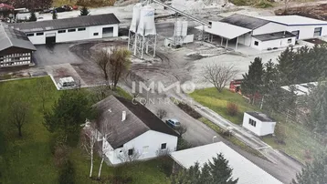 Luftaufnahme des gesamten Gewerbeareals mit mehreren Gebäuden, Lagerhallen, Silos und einem Wohnhaus.
