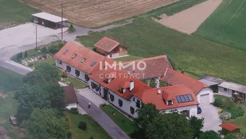 Luftaufnahme eines weitläufigen Anwesens mit mehreren Gebäuden und angrenzenden Feldern in ländlicher Umgebung.