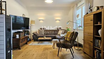 Gemütliches Wohnzimmer mit Holzboden, großem Sofa und einem modernen Kaminofen.