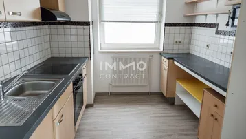 Funktionale Küche mit hellen Holzschränken, dunkler Arbeitsplatte und Fliesenrückwand.