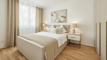 Helles Schlafzimmer mit Doppelbett, Nachttischen und großem Fenster für viel Tageslicht.