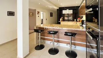 Offene Küche mit Frühstücksbar, Granitarbeitsplatte und modernen Einbaugeräten.