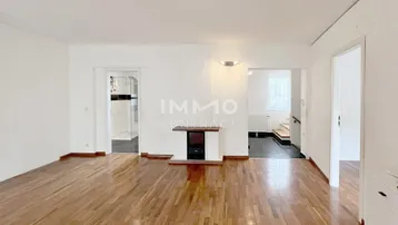 Geräumiges Wohnzimmer mit Holzboden und einem dekorativen Kamin, das viel Gestaltungspotenzial bietet.