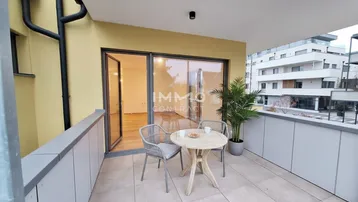 Geräumiger Balkon mit Sitzgelegenheiten und Blick in einen hellen, leeren Raum.