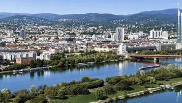 Panoramablick auf die Stadt Wien mit der Donau und den umliegenden Bergen im Hintergrund.
