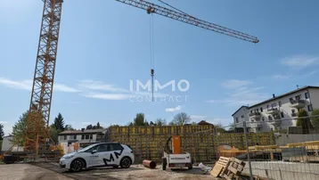 Baustelle mit großem Kran und im Bau befindlichem Gebäude unter blauem Himmel an einem sonnigen Tag.