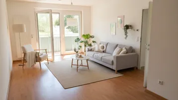 Helles Wohnzimmer mit Laminatboden, bequemer Couch und Zugang zum Balkon.