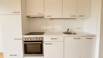 Moderne Einbauküche in Weiß mit integriertem Backofen und Kochfeld, ideal für kleine Wohnungen.