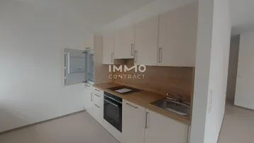 Kleine Einbauküche mit weißen Schränken, Holz-Arbeitsplatte und integrierten Geräten.