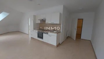 Helle Dachgeschosswohnung mit integrierter Küchenzeile und Schrägdachfenstern, ideal für Singles.