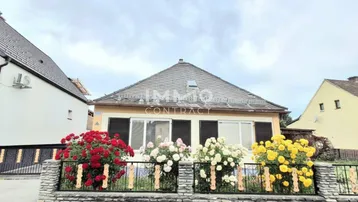 Traditionelles Einfamilienhaus mit Satteldach und gepflegtem Vorgarten mit Rosenbeeten.