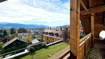 Geräumiger Holzbalkon mit weitem Blick über die Landschaft und Berge.