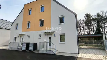Moderne Reihenhäuser mit heller Fassade und Carport-Zugang. Die Eingänge sind über kleine Treppen erreichbar.
