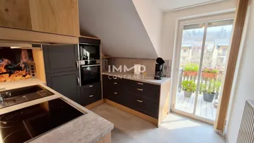 Moderne Küche mit dunklen Schränken, integrierten Geräten und Zugang zu einem kleinen Balkon.