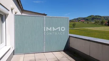 Geräumige Terrasse mit Fliesenboden, Sichtschutz und weitem Blick über die grüne Landschaft.