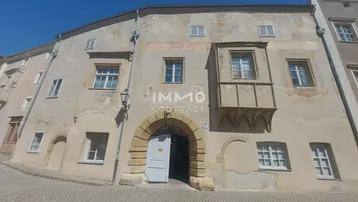 Altes Gebäude mit historischer Fassade und Erker an einer gepflasterten Straße.