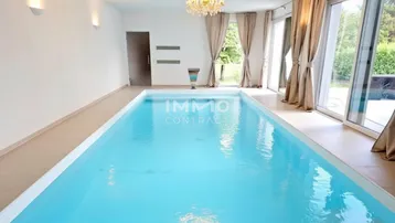 Heller Innenpoolbereich mit großen Fenstern und Kronleuchter, ideal für Entspannung und Sport.