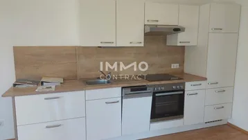 Moderne Einbauküche mit weißen Schränken, Holzarbeitsplatte und integrierten Geräten.