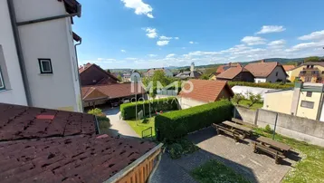Blick von oben auf den gemeinschaftlichen Gartenbereich mit Sitzgelegenheiten und umliegenden Häusern.