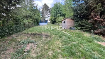 Großer, abfallender Gartenbereich mit Rasenfläche, Gartenhaus und einem Pool im Hintergrund.