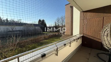 Sonniger Balkon mit Sicherheitsnetz und Blick auf den grünen Gartenbereich.