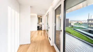 Heller Flur mit Holzparkettboden und Zugang zu einer großen Dachterrasse mit Grünfläche.