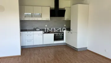 Moderne Einbauküche mit weißen Schränken, schwarzer Dunstabzugshaube und Holzboden in offenem Wohnbereich.