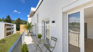 Heller Balkon mit modernen Fliesen, Sitzgelegenheiten und Blick auf die Umgebung.
