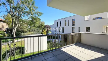 Heller Balkon mit Fliesenboden und Blick auf die grüne Umgebung und moderne Gebäude.
