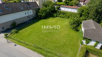 Luftaufnahme eines unbebauten Grundstücks mit umliegenden Häusern und viel Grün.