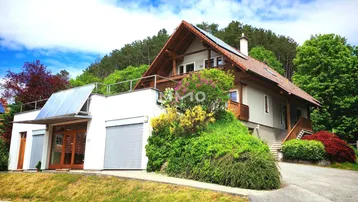 Modernes Einfamilienhaus mit Satteldach, Photovoltaikanlage und integrierter Garage in grüner Umgebung.
