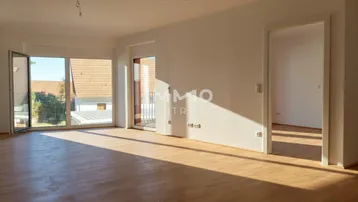 Helles, leeres Zimmer mit Parkettboden und Zugang zu einem Außenbereich, ideal für einen Wohnbereich.