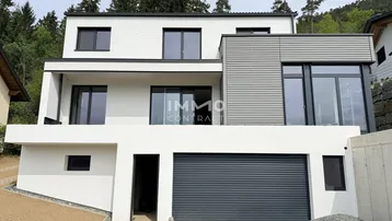 Moderne Hausfassade mit weißem Putz, grauen Akzenten und integrierter Garage.