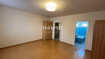 Geräumiger Innenraum mit Linoleumboden und Zugang zu einem Badezimmer, in gutem Zustand.
