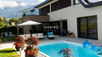 Moderner Außenbereich mit Pool, gemütlicher Sitzecke, gepflegtem Rasen und beeindruckendem Bergblick.