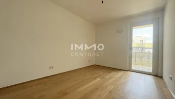 Helles Schlafzimmer mit Holzboden und Zugang zu einem kleinen Balkon oder einer französischen Balkontür.