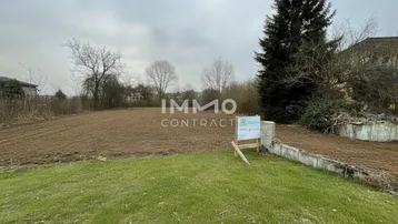 Leeres Grundstück mit vorbereitetem Boden und umliegender Vegetation, ideal für Neubauprojekte.
