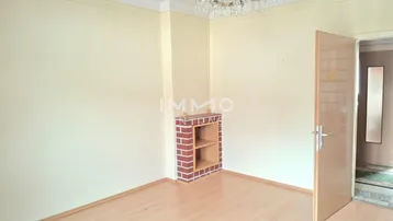 Helles Wohnzimmer mit Laminatboden, dekorativem Kamin und Kronleuchter.