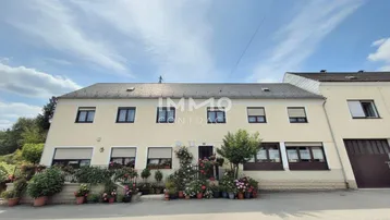 Traditionelles Wohnhaus mit Blumenkästen und gepflegter Fassade unter blauem Himmel.