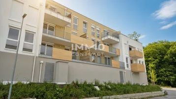 Moderne Wohnanlage mit mehreren Balkonen und heller Fassade unter blauem Himmel.