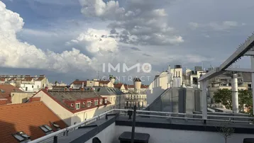 Dachterrasse mit weitem Blick über die Dächer der Stadt unter einem bewölkten Himmel.